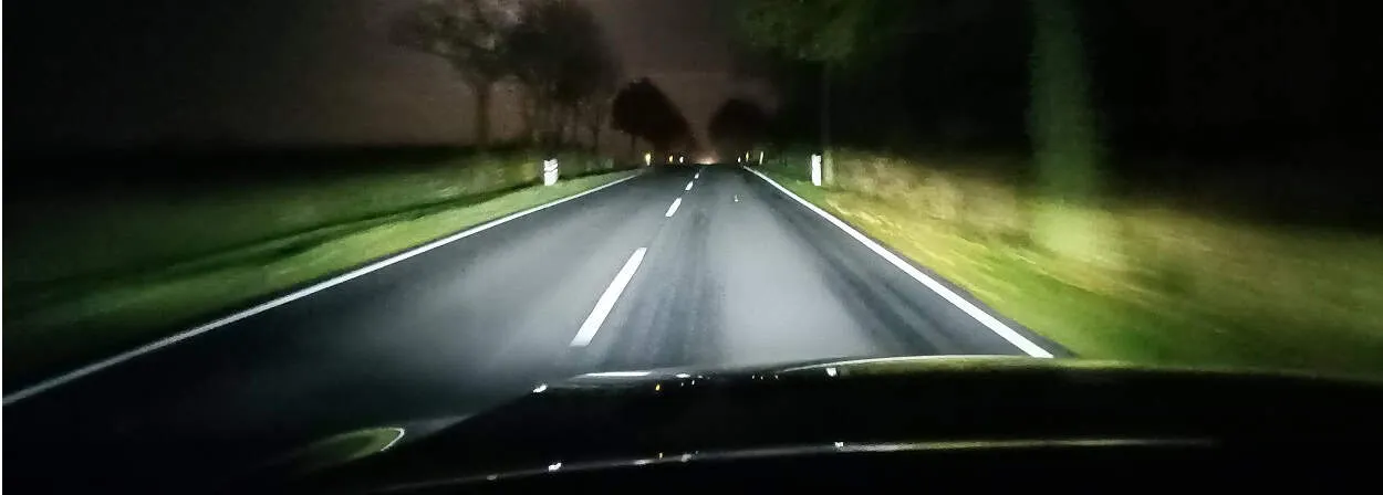 Nachtstraße mit eingeschaltetem Scheinwerfer