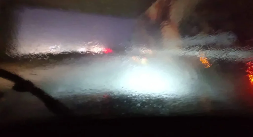 Verschwommene Sicht durch regennasses Autofenster bei Nacht.