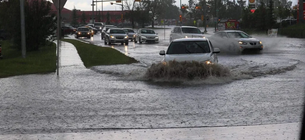 Autos fahren durch überflutete Straße im Regen.
