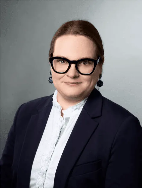 Porträt einer Frau mit Brille und dunkelblauem Sakko.