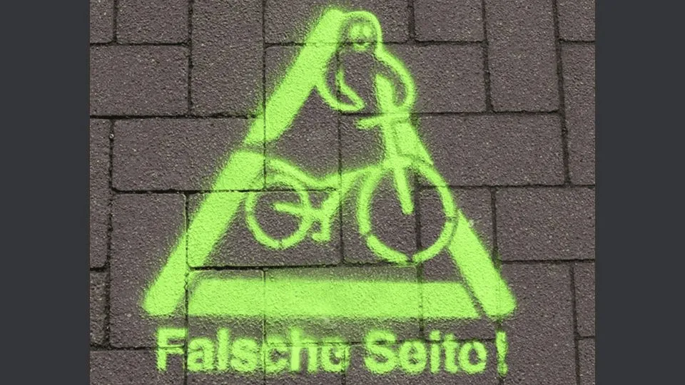 Graffiti mit Fahrrad und Text 'Falsche Seite!'