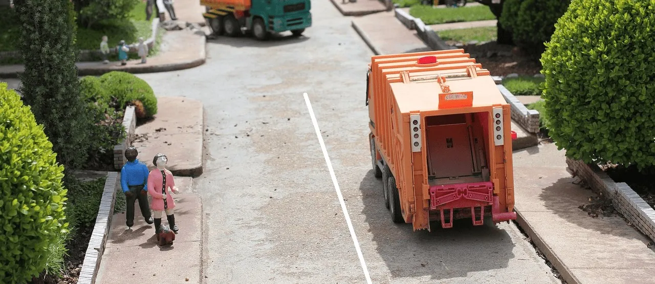 Spielzeug-Müllwagen in Miniaturstraße mit Figuren