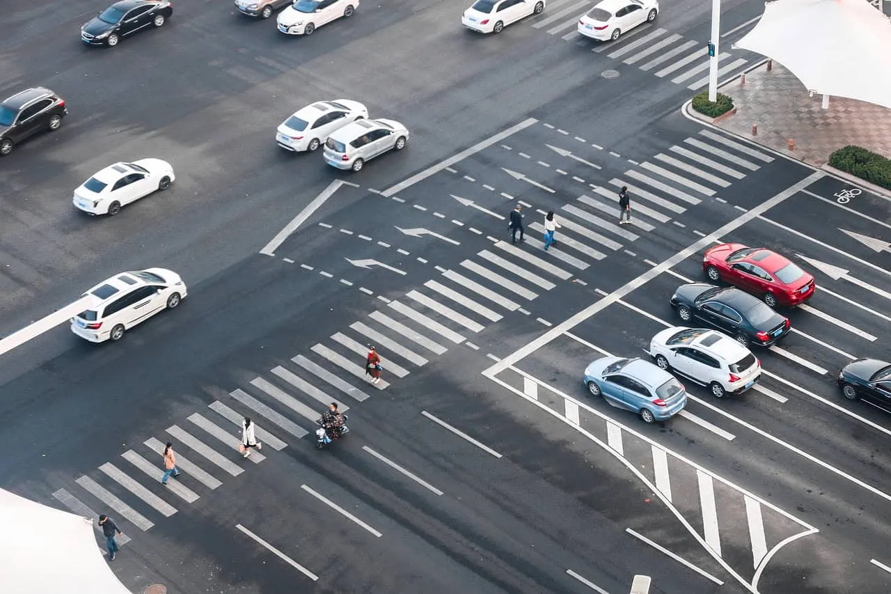 Straßenkreuzung mit Autos und Fußgängern gesehen von oben.